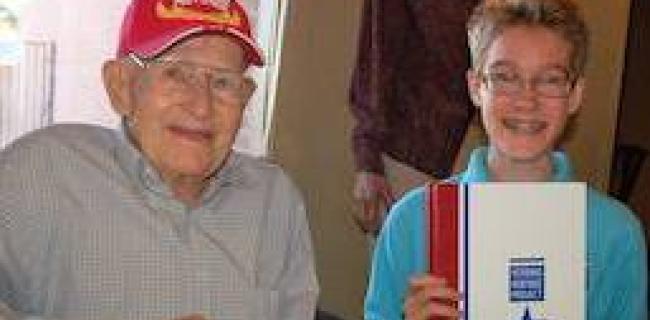 WWII Marine with Middle School Boy holding 2016 edition of SYA