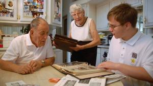 Student Interviewing Veteran with wife bringing photo album